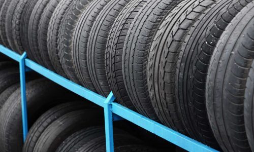 Rack with variety of car tires in automobile store. Many black tires. Tire stack background. Selective focus