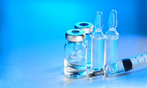Medical vials for injection with a syringe and ampules on blue background